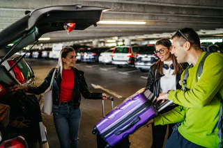 Cheerful friends loading luggage into the car