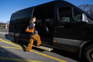 Une passagère embarque dans la navette reliant les parkings éloignés au terminal de Genève Aéroport, un service inclus pour rejoindre votre vol rapidement et confortablement.