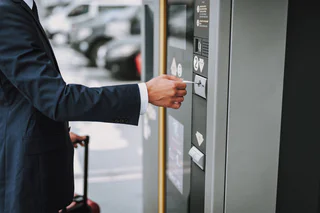 Un voyageur règle son stationnement à la borne de paiement automatique du parking de Genève Aéroport, une solution rapide et pratique.