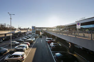 Vue panoramique du parking extérieur P2 de Genève Aéroport, situé à proximité immédiate du terminal, avec passerelle d'accès piéton.
