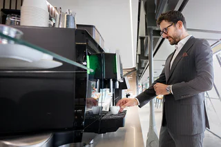 Espace détente et services business à l'Aéroport de Genève : un voyageur d'affaires profite du buffet café