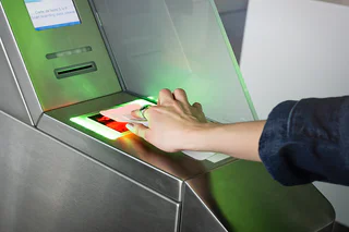 Une passagère scanne sa carte d'embarquement numérique sur un lecteur automatique à l'entrée de la voie prioritaire. Ce service de coupe-file, permet de contourner les files d'attente standard pour un gain de temps optimal avant votre vol.
